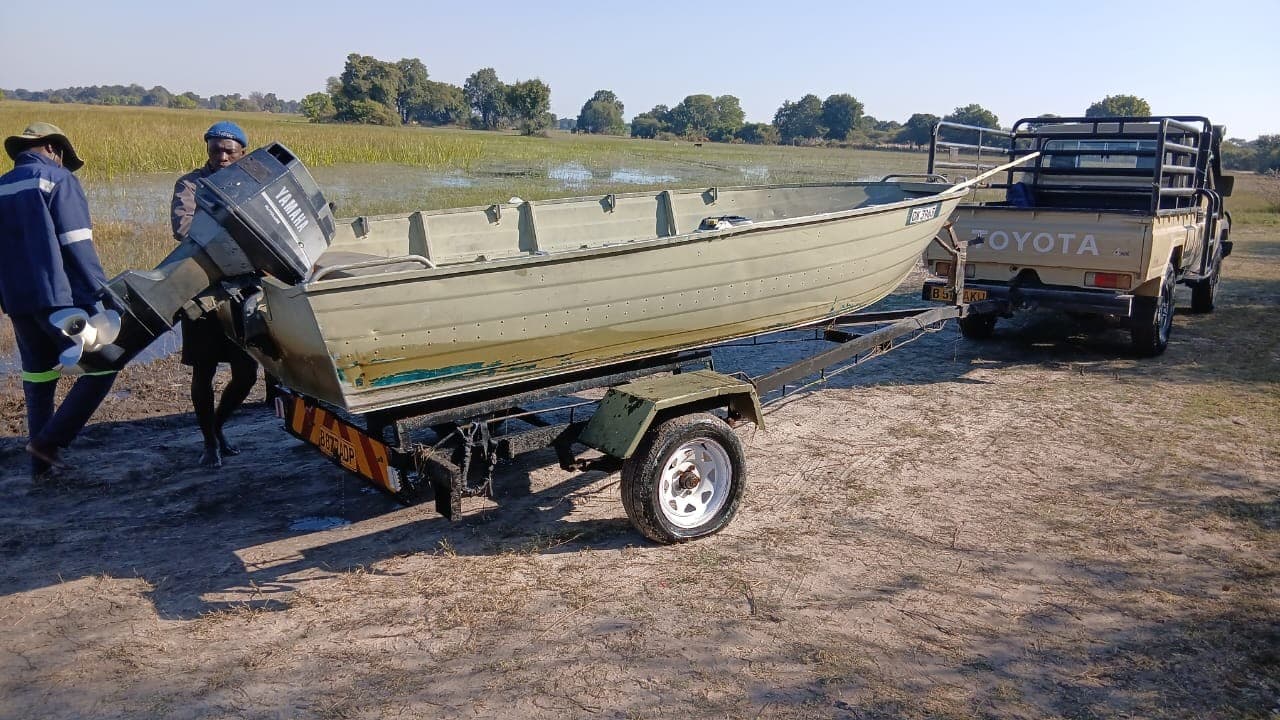 Boat being loaded onto a trailer behind a 4x4 at the edge of the Okavango Delta floodplain.