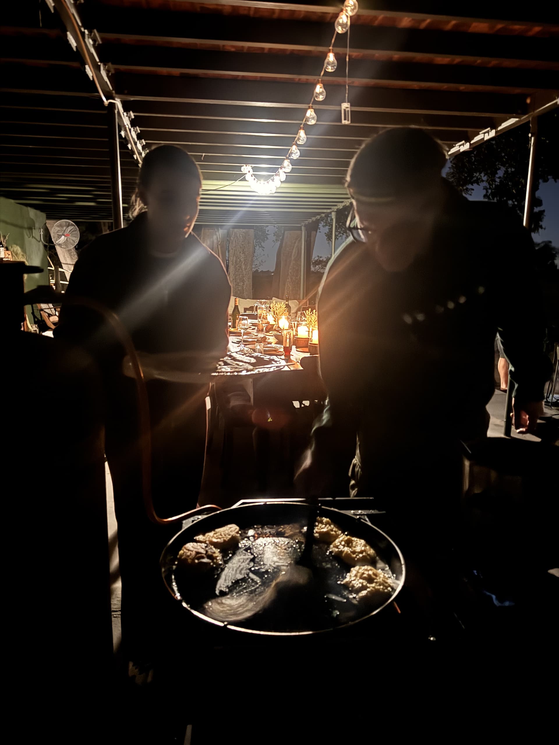 Chefs preparing a meal over an open flame under string lights during a boma dinner at Samonyana.