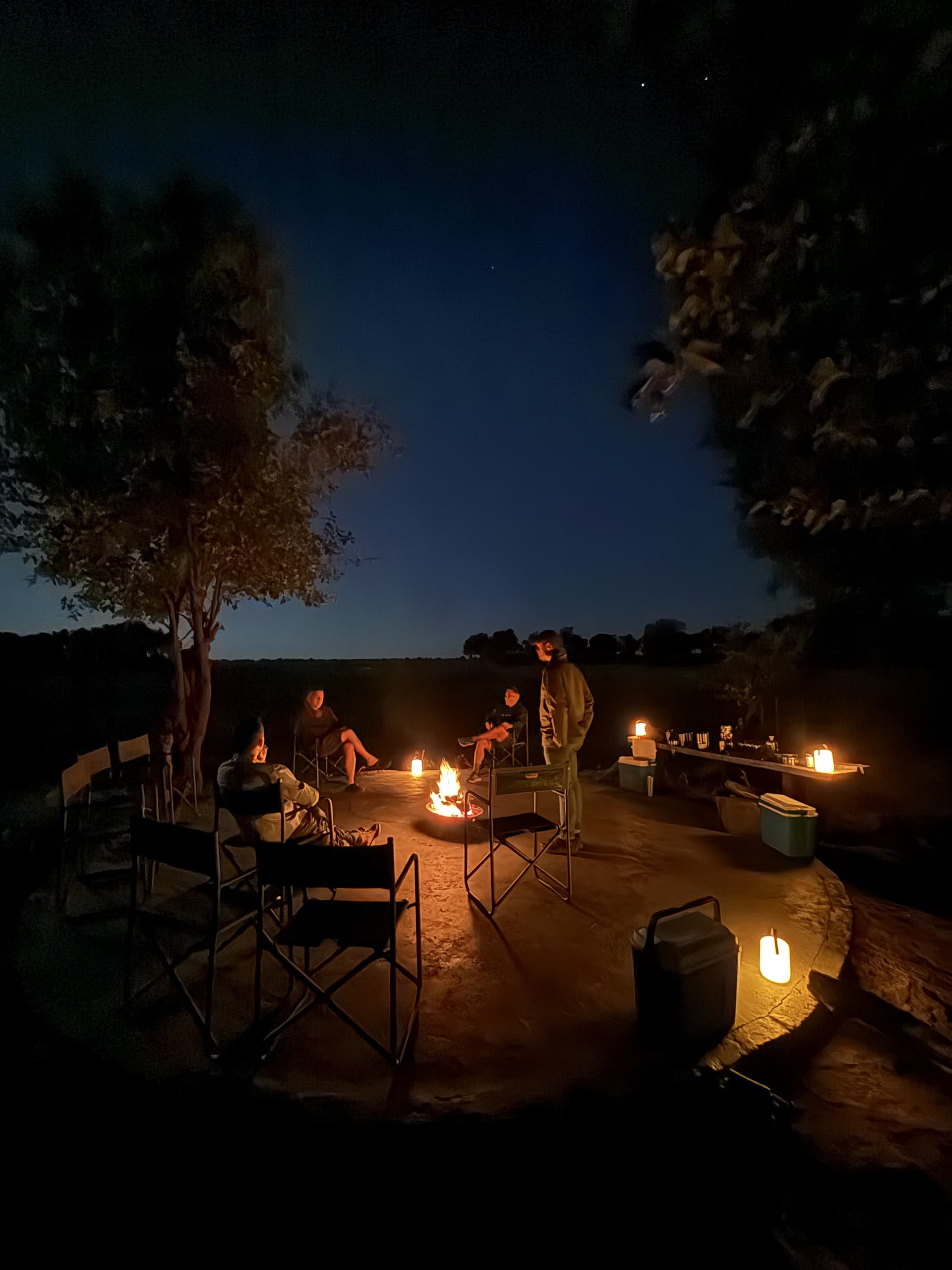 Guests relaxing around a campfire beneath a darkening dusk sky at Samonyana Private Island