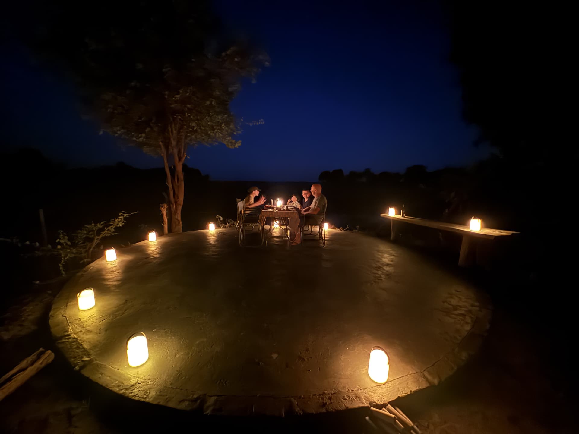 Guests seated together for a candlelit dinner under a night sky at Samonyana Private Island