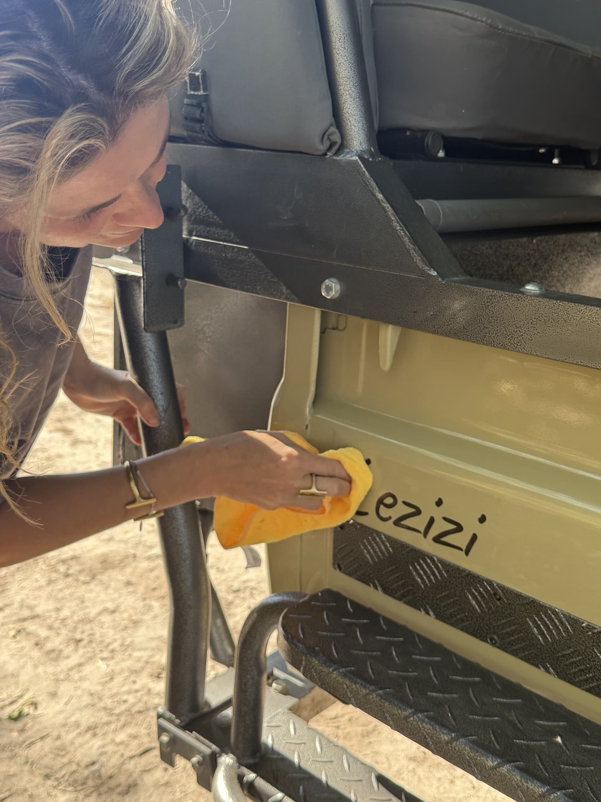 Staff member polishing the open safari game-drive vehicle in bright daylight at Samonyana Private Island.