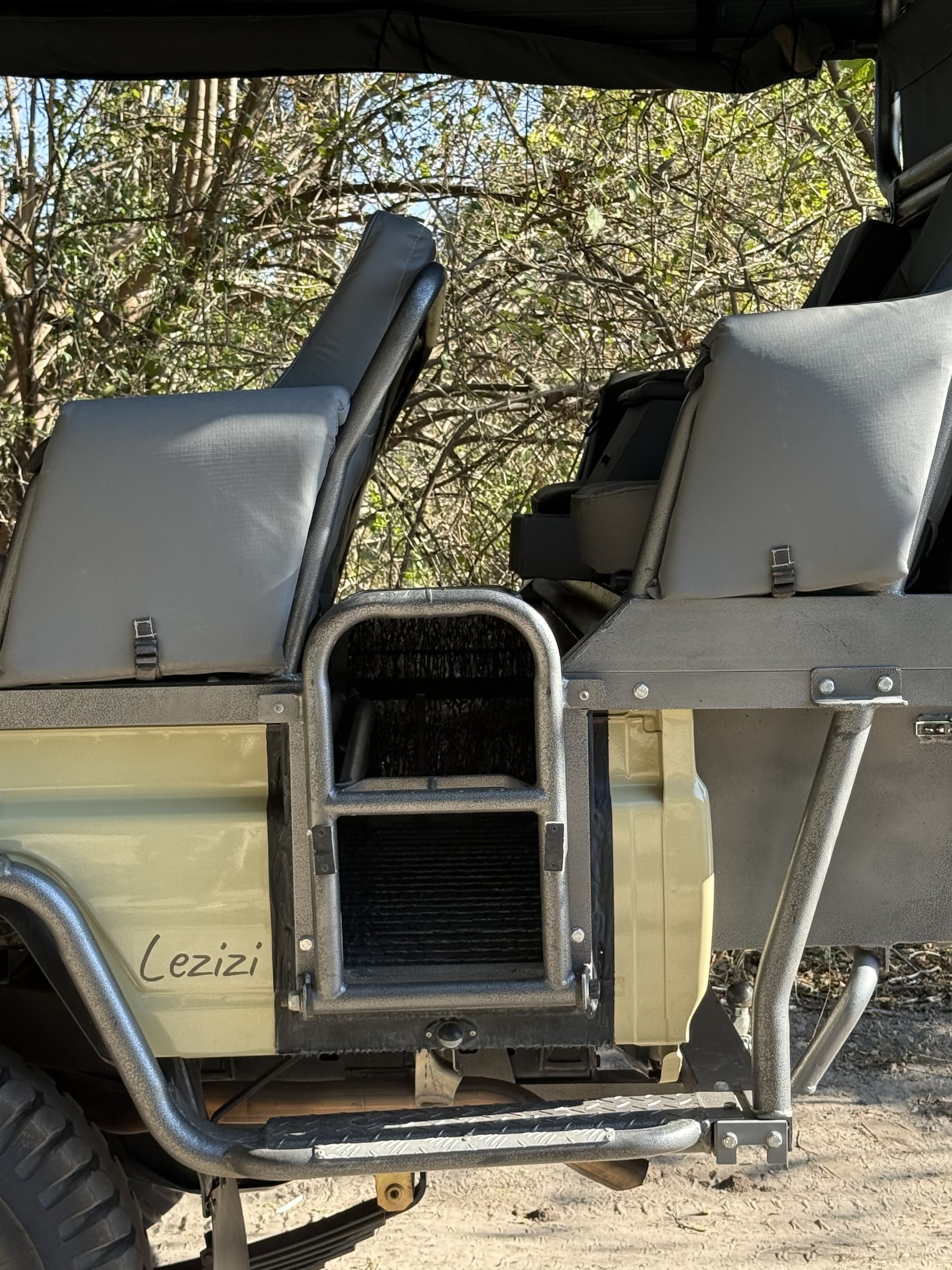 Open-sided safari game-drive vehicle with tiered bench seating parked among the trees at Samonyana Private Island.