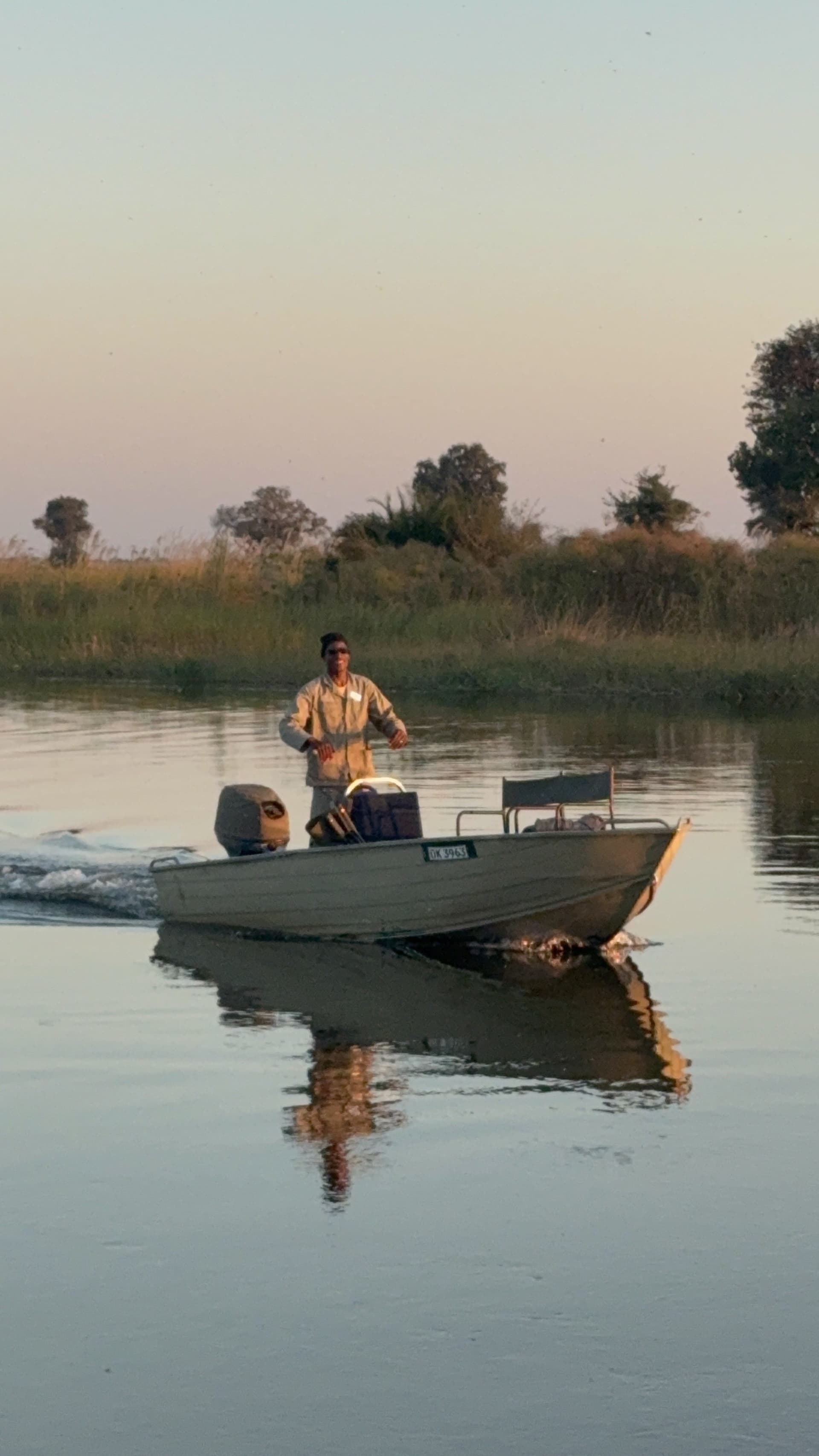 Guide steering a boat across calm water at sunset near Samonyana Private Island.