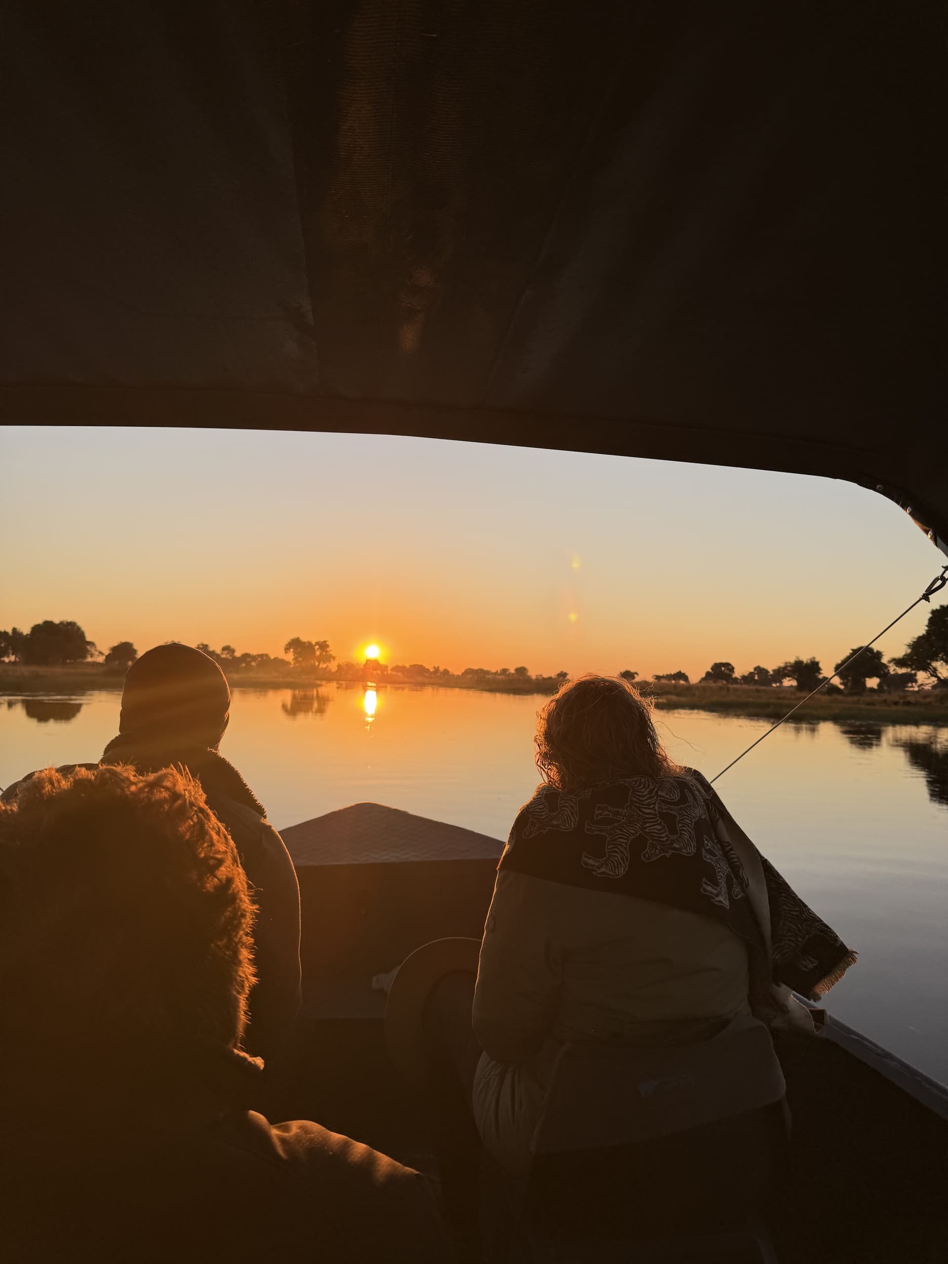 Guests aboard a boat watching the sun set over the Okavango Delta at Samonyana.