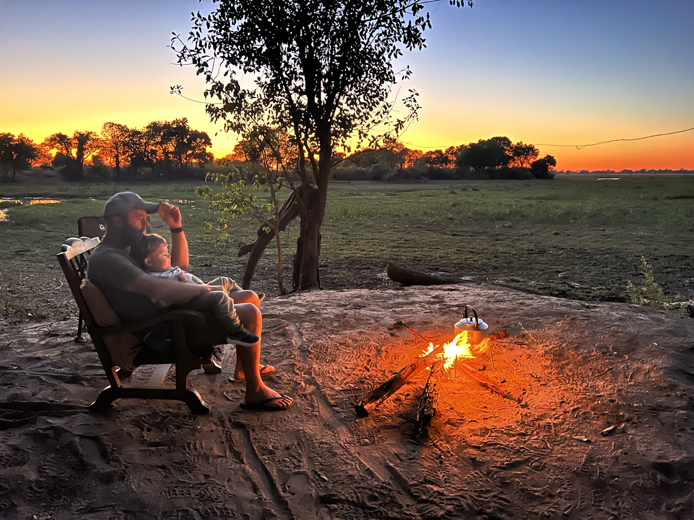 Parent and child at the campfire as the sun sets